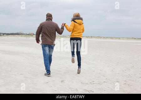 Un jeune couple promenades sur la plage de sable dans l'hiver Banque D'Images