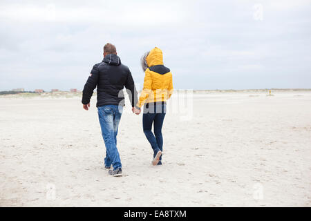 Un jeune couple promenades sur la plage de sable dans l'hiver Banque D'Images