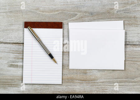 Vue de dessus de l'enveloppe d'affaires et de l'écriture avec stylo bloc-notes sur le bureau en bois blanc rustique Banque D'Images