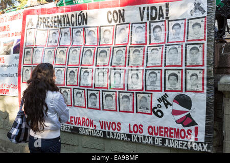 Personnes voir une bannière exiger la justice pour les étudiants, exécutés par des policiers corrompus se suspendre à la place principale, le 8 novembre 2014 à Oaxaca, au Mexique. Les 43 élèves absent pendant plus de six semaines sont présumée morte après des restes humains calcinés ont été pêché d'une rivière et ses rives le 7 novembre 2014. Banque D'Images