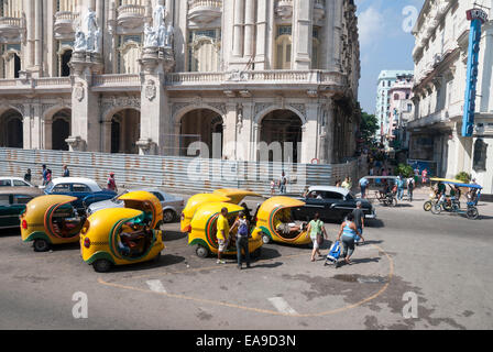 Des taxis coco jaunes distinctifs attendent les touristes lorsqu'ils sont garés en face du Théâtre National sur le Paseo del Prado dans le centre de la Havane Cuba Banque D'Images