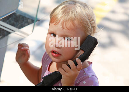 Portrait plein air de petite blonde girl talking on the street phone Banque D'Images