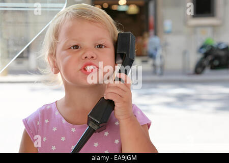 Portrait de plein air peu Caucasian girl talking on the street phone Banque D'Images