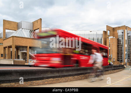 Blurred motion image des cyclistes et des bus rouges à Kingston, London, UK - voie cyclable séparée de la circulation par un mur. Banque D'Images