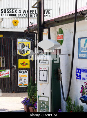 Une pompe à essence d'époque dans un garage à Wiston, West Sussex, UK avec d'affiches publicitaires pour des marques telles que Michelin, Castrol et Val Banque D'Images