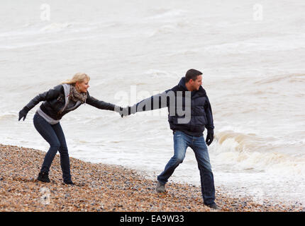 Un couple ludique bénéficiant d'une journée au bord de la région de Brighton de vêtements chauds pour l'hiver Banque D'Images