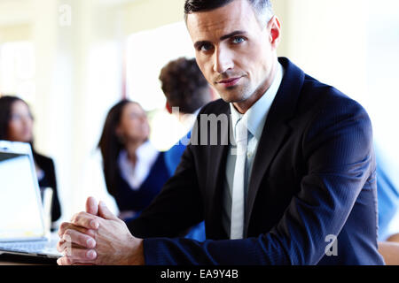 Serious businessman assis à la table devant des collègues Banque D'Images