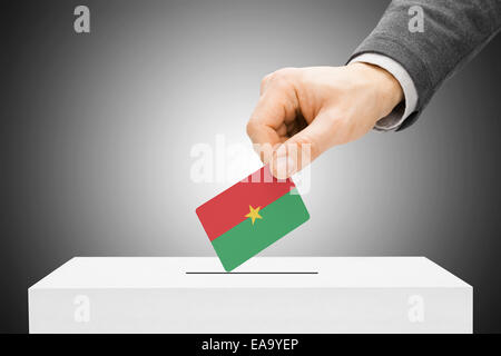 Concept de vote - Hommes de l'insertion d'un drapeau en urne - Burkina Faso Banque D'Images