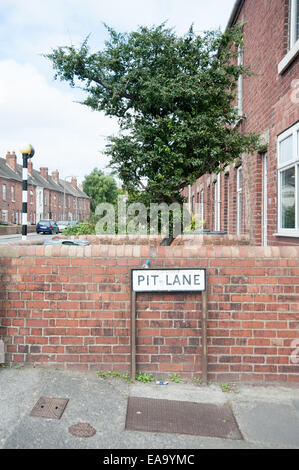 Panneau de rue pour Pit Lane à Treeton, South Yorkshire, situé contre des maisons mitoyennes en briques rouges et un arbre verdoyant dans une rue résidentielle calme Banque D'Images