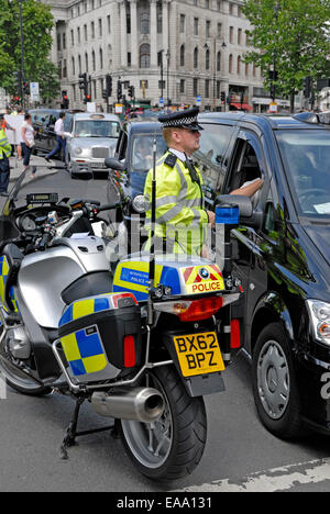 Londres, Angleterre, Royaume-Uni. Les chauffeurs de taxi noir différend, 2014. Agent de police moto parlant à un chauffeur de taxi Banque D'Images