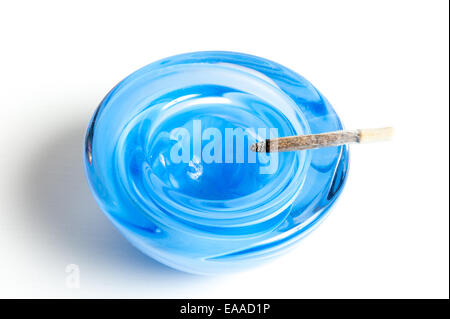 Un cendrier en verre bleu avec un fumeur de cigarettes fait main isolé sur fond blanc Banque D'Images