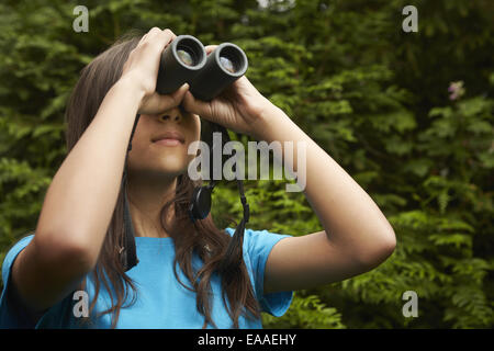 Une jeune fille avec l'observation des oiseaux des jumelles. Banque D'Images