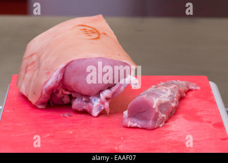 Porc joint sur une planche à découper rouge viande crue Banque D'Images