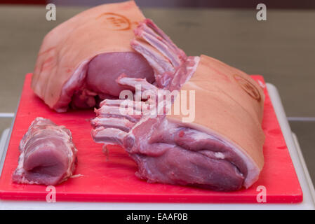 Porc joint sur une planche à découper rouge viande crue Banque D'Images