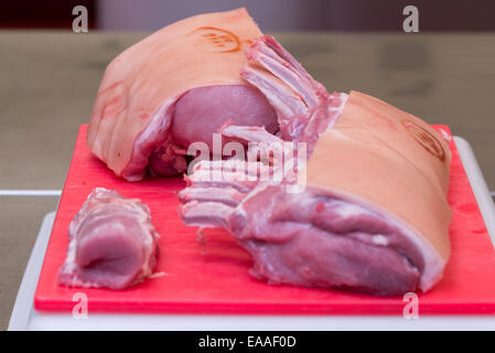 Porc joint sur une planche à découper rouge viande crue Banque D'Images