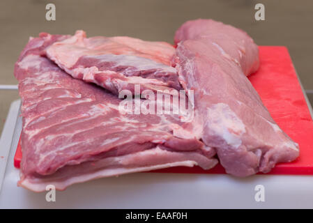 Porc joint sur une planche à découper rouge viande crue Banque D'Images