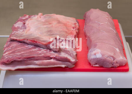 Porc joint sur une planche à découper rouge viande crue Banque D'Images