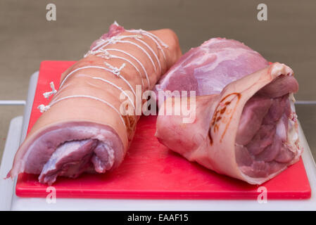 Porc joint sur une planche à découper rouge viande crue Banque D'Images