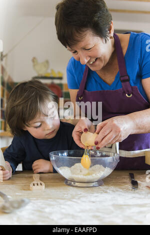 Une femme et un enfant de la cuisson à une table de cuisine, faire des gâteaux de fées. Banque D'Images