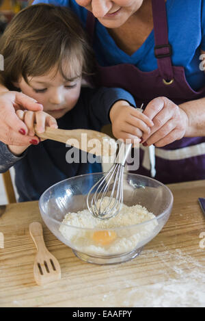 Une femme et un enfant de la cuisson à une table de cuisine, faire des gâteaux de fées. Banque D'Images