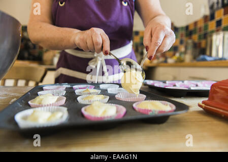 Une femme à une table de cuisine la cuisson des gâteaux de fées. Banque D'Images