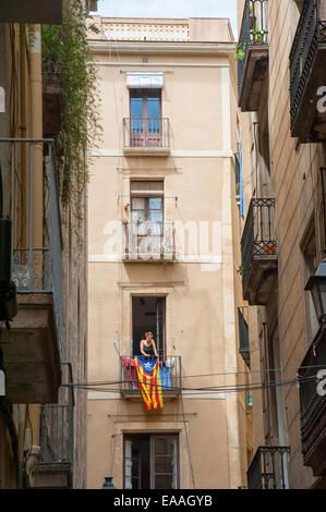 Jeune femme étendre le linge sur son balcon drapé de drapeau catalan dans le quartier gothique de Barcelone, Catalogne, Espagne Banque D'Images