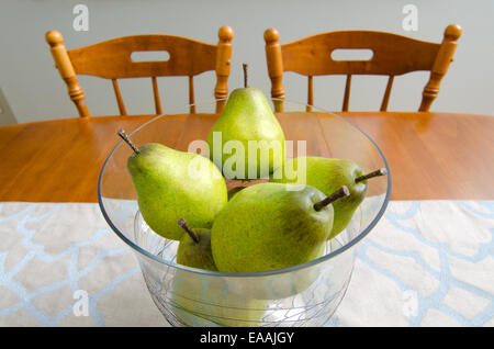 Poires : Les poires dans un bol en verre créer un centre de table décoratif pour une table à manger. Banque D'Images