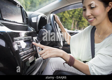 Une jeune femme assise dans sa voiture. Banque D'Images