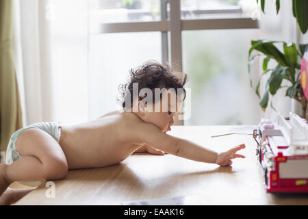 Baby Boy de grimper sur une table. Banque D'Images