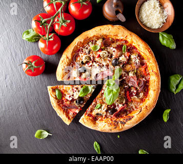 Frais fait maison pizza italienne avec légumes. Servi sur la surface de la pierre noire. Tourné à partir de la vue supérieure Banque D'Images