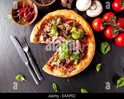 Frais fait maison pizza italienne avec légumes. Servi sur la surface de la pierre noire. Tourné à partir de la vue supérieure Banque D'Images