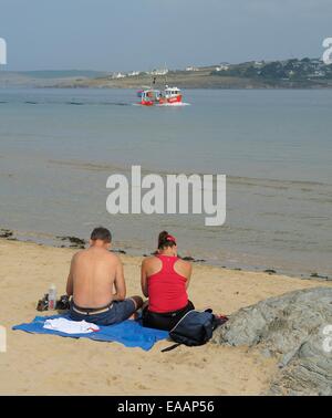 Un homme et une femme assis sur la plage dans le Camel Estuary, Padstow, Cornwall, Angleterre Royaume-Uni Banque D'Images