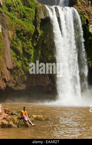 Portrait vertical d'un jeune homme assis sur un rocher à Cascades d'Ouzoud sur une journée ensoleillée. Banque D'Images