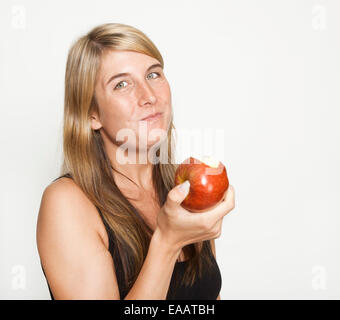 Jeune femme aux cheveux longs est titulaire d'une pomme rouge dans la main, fond blanc Banque D'Images