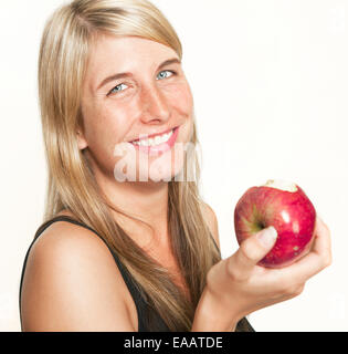 Jeune femme aux cheveux longs est titulaire d'une pomme rouge dans la main, fond blanc Banque D'Images