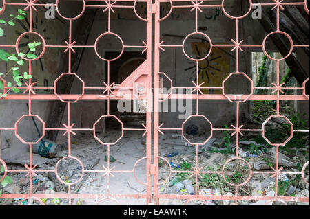 Vue de l'intérieur des bâtiments délabrés maison coloniale espagnole à travers un portail en fer forgé couleur saumon, Campeche, Mexique. Banque D'Images