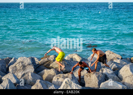 Miami Beach Florida, South Pointe Park Pier, jetée de l'océan Atlantique, brise-lames, rochers, adultes adultes homme hommes, amis, escalade, voyages des visiteurs Banque D'Images