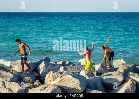 Miami Beach Florida, South Pointe Park Pier, jetée de l'océan Atlantique, brise-lames, rochers, adultes adultes homme hommes, amis, escalade, voyages des visiteurs Banque D'Images