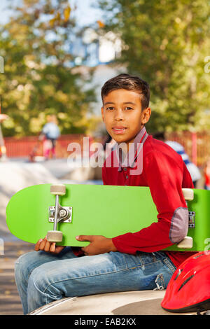 Vue de l'Arabian Boy with Green skateboard assis Banque D'Images