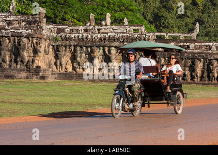 Cambodge, Angkor Thom. Moto-taxi alimenté en passant devant les Terrasse des éléphants. Banque D'Images