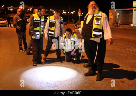 Bethléem. 10 Nov, 2014. Les médecins israéliens et les membres des services religieux chercher des traces de sang alors qu'ils nettoyer la scène à un arrêt de bus près de la colonie juive d'Alon Shvut près de la ville cisjordanienne de Bethléem, où une femme juive aurait été poignardé à mort par un Palestinien, le 10 novembre 2014. L'agresseur présumé, un Palestinien dans la trentaine identifiés comme Maher al-Hashlamun, aurait tenté de jeter son véhicule vers un arrêt de bus et puis a commencé à poignarder les gens. Il aurait été blessé par un garde de sécurité sur les lieux. Credit : Luay Sababa/Xinhua/Alamy Live News Banque D'Images