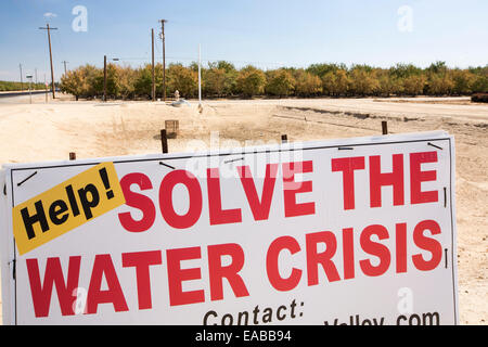 Un signe d'agriculteurs à propos de la crise de l'eau à côté d'un point d'eau asséché les agriculteurs, un suivant 4 l'année de la sécheresse, près de Bakersfield dans la Central Valley, Californie, USA, avec le sol s'est tourné vers la poussière. L'ensemble de la Californie est dans une sécheresse catastrophique avec $2.2 milliards de dollars par année perdue par le secteur agricole, avec de nombreux travailleurs mis à pied. Un tiers des enfants en Californie en ce moment vont au lit le ventre vide. 428 000 hectares de terres agricoles ont été retirées de la production dans la vallée centrale en raison de la sécheresse. Banque D'Images