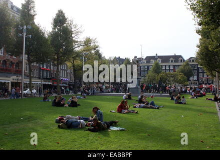 Rembrandtplein, le centre-ville d'Amsterdam aux Pays-Bas. Des gens assis sur l'herbe, les jeunes touristes étrangers profitant du soleil. Banque D'Images