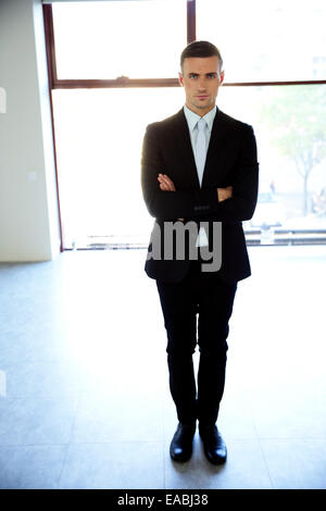 Full Length portrait of a businessman standing with arms folded at office Banque D'Images