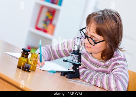 La science des ados fille sur le cours de biologie avec microscope et des échantillons, l'écriture de l'expérience résultats Banque D'Images