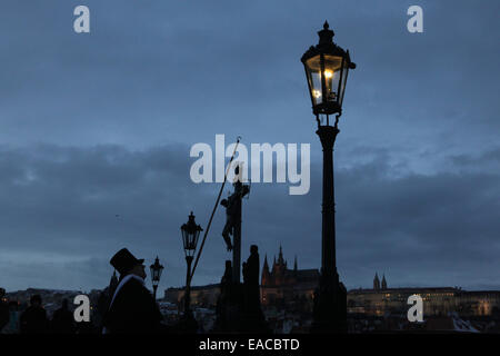 Le Lamplighter allume un feu de gaz rue manuellement durant l'Avent au pont Charles à Prague, République tchèque. Street ga Banque D'Images