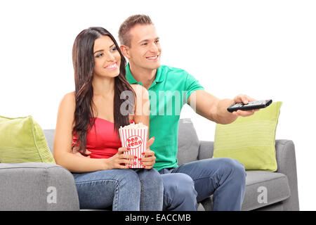 Jeune couple watching TV assis sur un canapé isolé sur fond blanc Banque D'Images