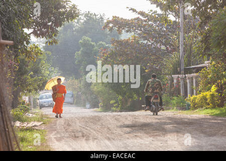 Le moine bouddhiste avec parapluie marche à travers Ban Xang Khong village près de Luang Prabang, Laos, Asie du Sud Est, Asie, Banque D'Images