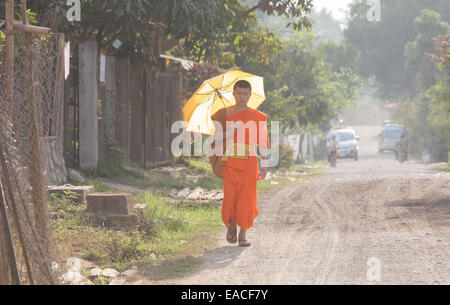 Le moine bouddhiste avec parapluie marche à travers Ban Xang Khong village près de Luang Prabang, Laos, Asie du Sud Est, Asie, Banque D'Images