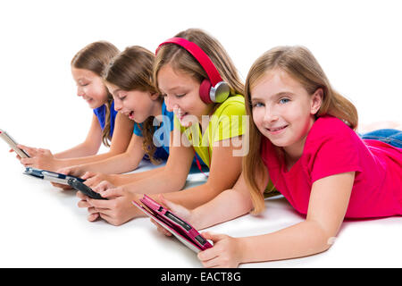 Sœurs cousins kid filles avec des comprimés de haute technologie et smatphones consécutive couché sur fond blanc Banque D'Images